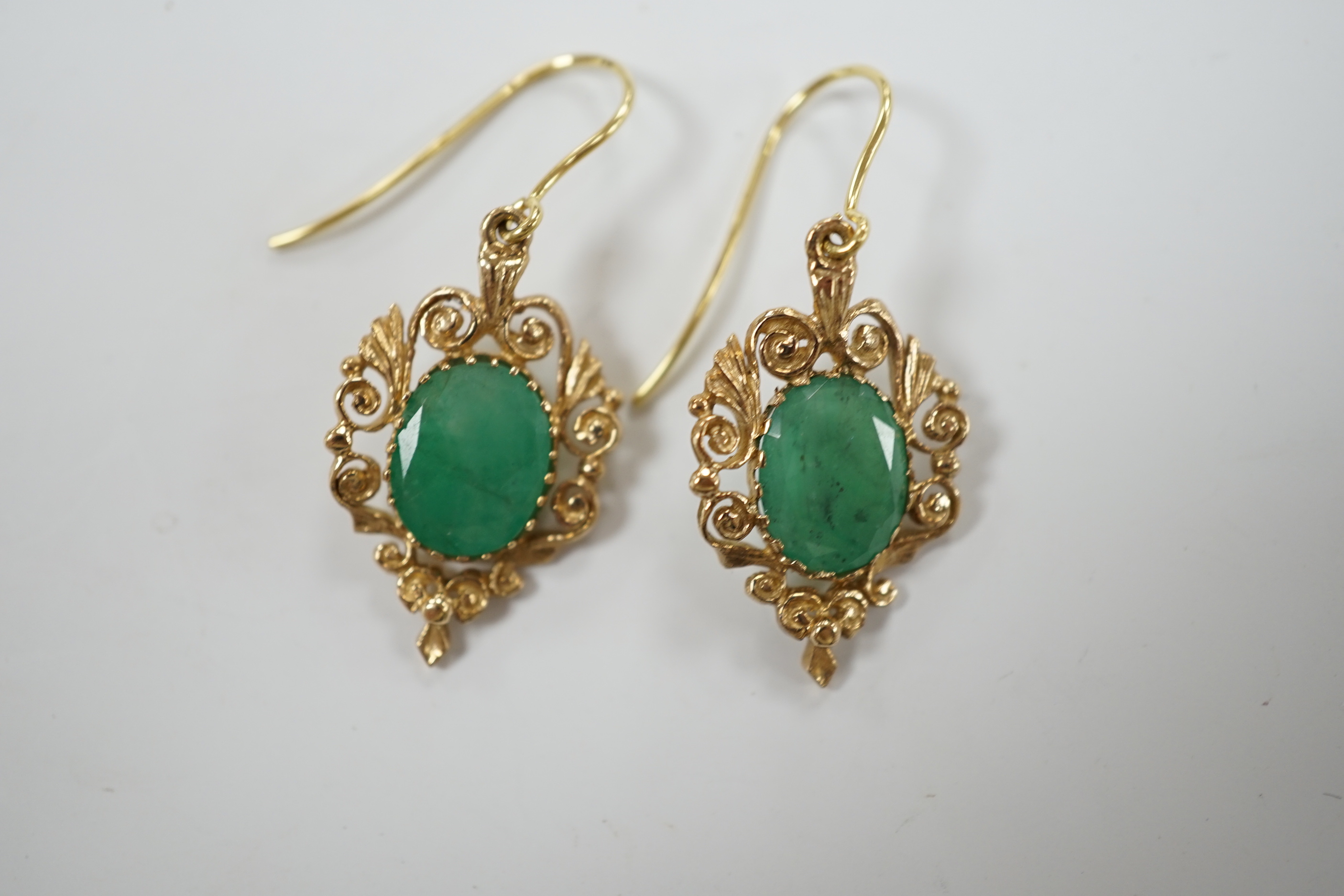 A pair of yellow metal and oval cut emerald set drop earrings, 23mm, gross weight 3.8 grams.